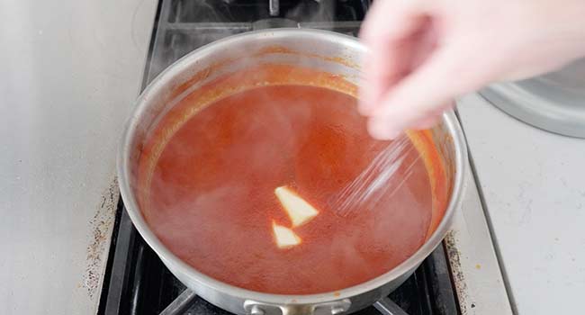 adding butter and salt to tomato sauce