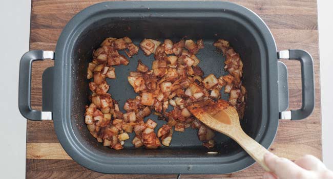 mixing tomato paste into caramelized onions