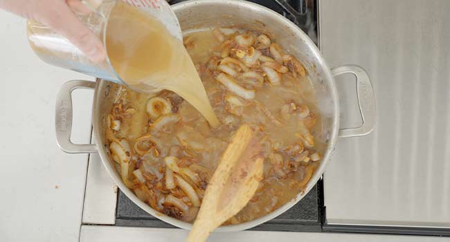 pouring beef stock int a pot of onions