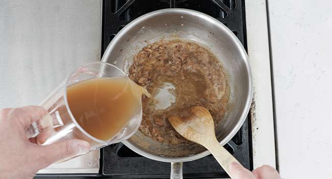 adding beef stock to roux and onions