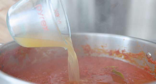 adding chicken stock to tomato sauce