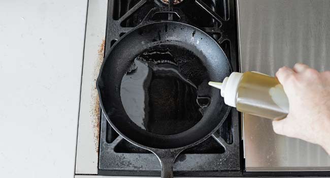 adding oil to a cast iron pan