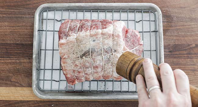 adding pepper to a beef roast