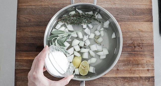 adding salt to a pot of brine