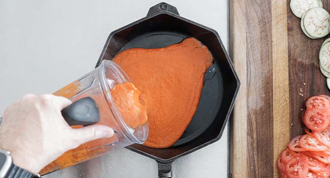 adding tomato and pepper puree to a skillet