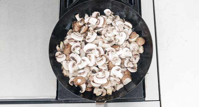 adding raw mushrooms to a hot pan