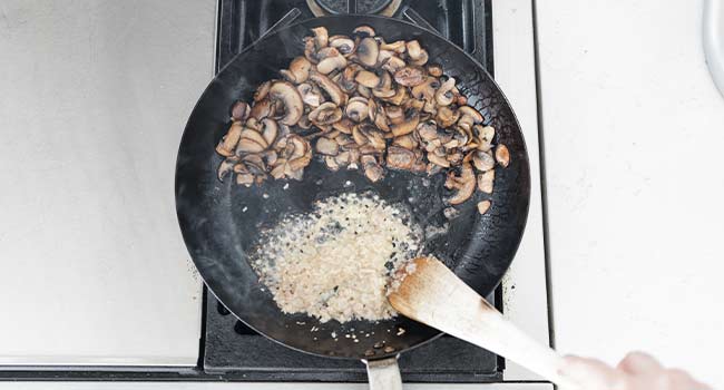 cooking shallots and garlic in butter next to mushrooms