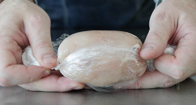 rolling up chicken in plastic wrap