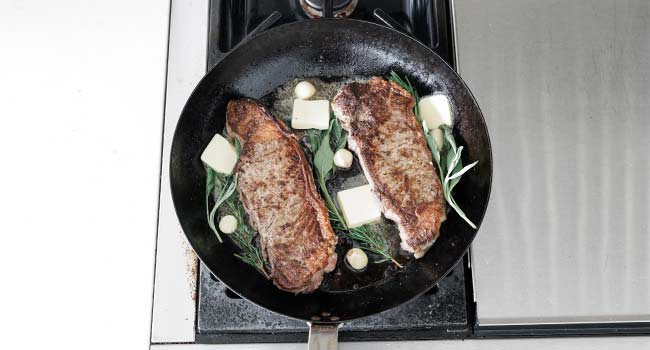 butter and herbs in a pan with steak