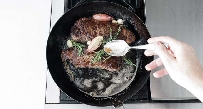 basting steaks with butter and herbs