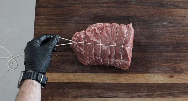 cutting twine on a trussed piece of beef