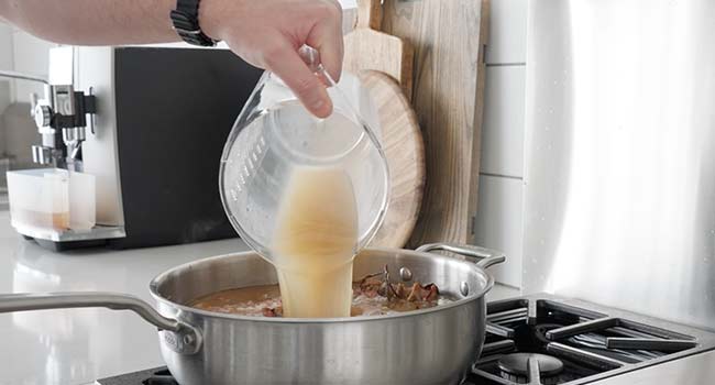 pouring chicken stock in a pot