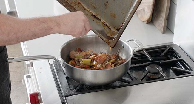 adding wine and fond to a pot of roasted veggies