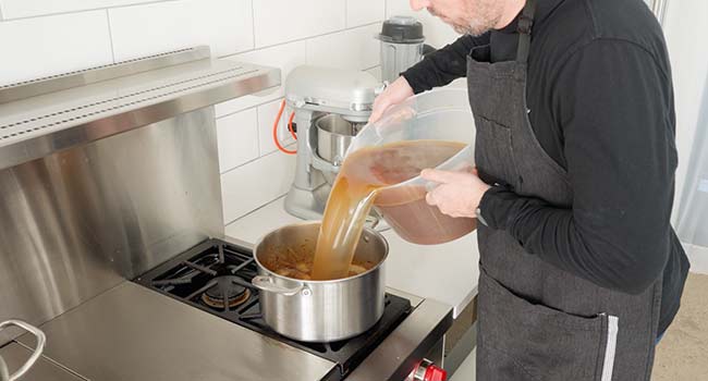 adding veal stock to a pot