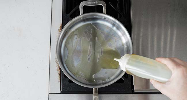 adding oil to a saucepan