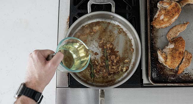 adding white wine to a pan