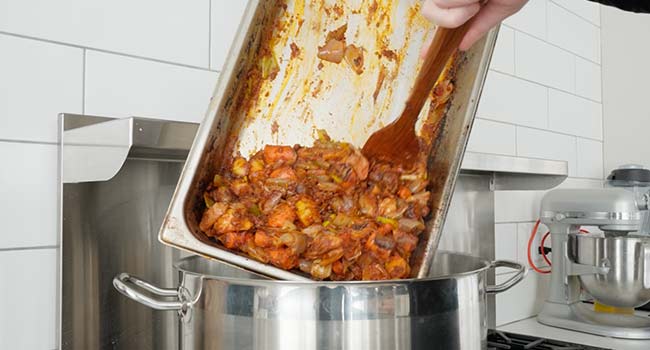 adding tomato paste veggies to a pot