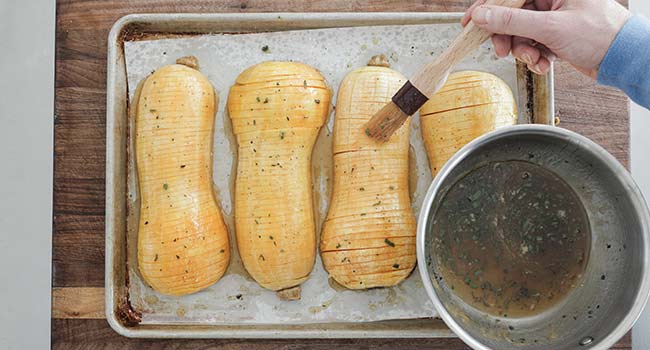 brushing hasselback butternut squash with a maple glaze