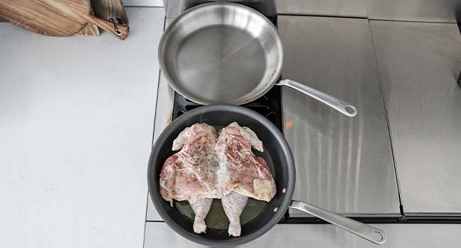 chicken cooking in a pan with oil