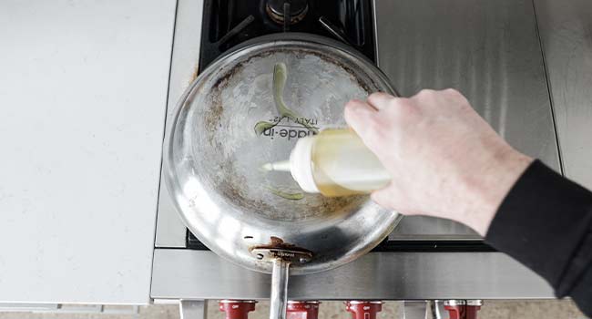 drizzling oil onto the bottom of a pan