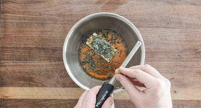 adding nutmeg to a pot of butter and maple syrup