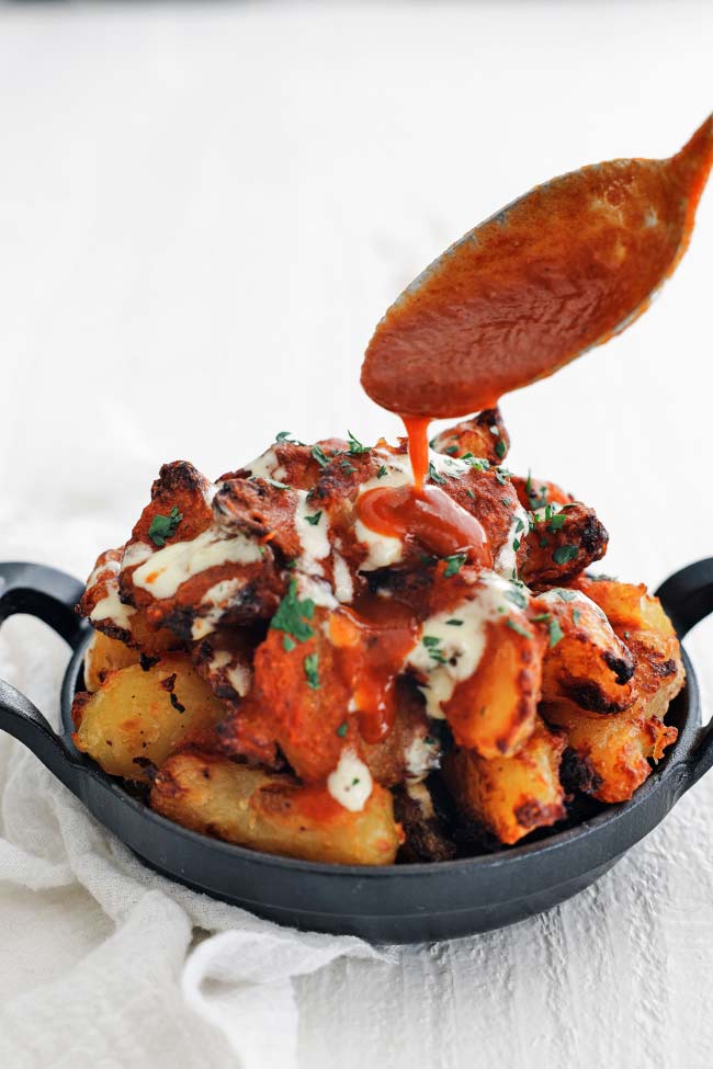 adding sauce to patatas bravas