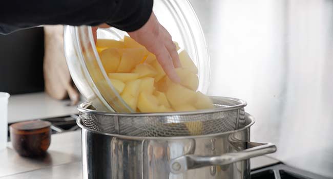 adding potatoes to a pot of boiling water