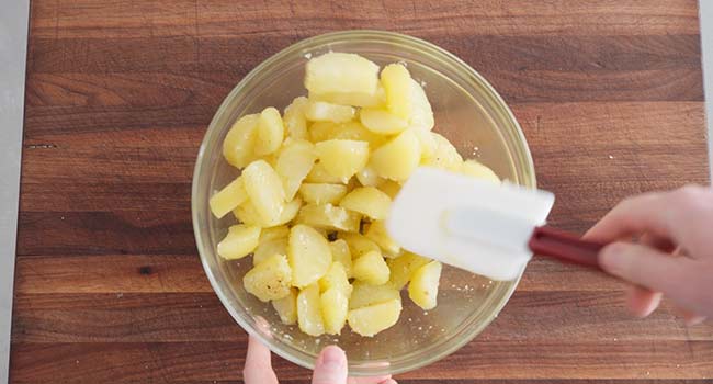 folding seasonings and olive oil with cooked potatoes