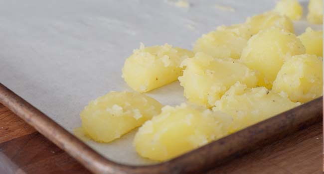 adding potatoes to a sheet tray