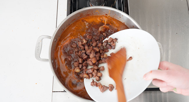 adding cooked beef to a pot of beef stock