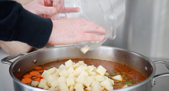 adding vegetables to a beef soup