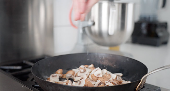 adding mushrooms to a pan