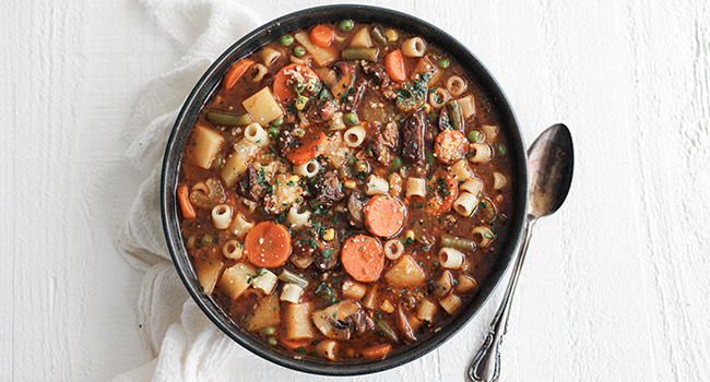 vegetable beef soup in a bowl with herbs