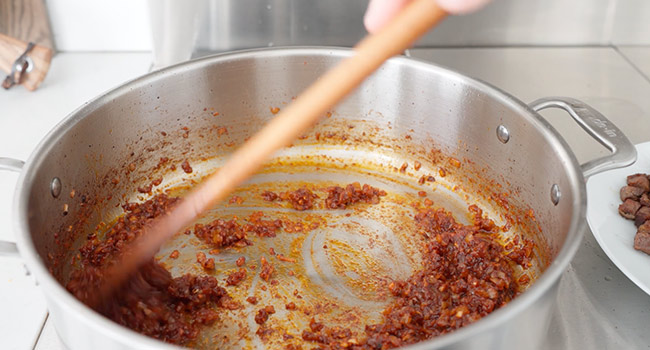 stirring tomato paste into onions