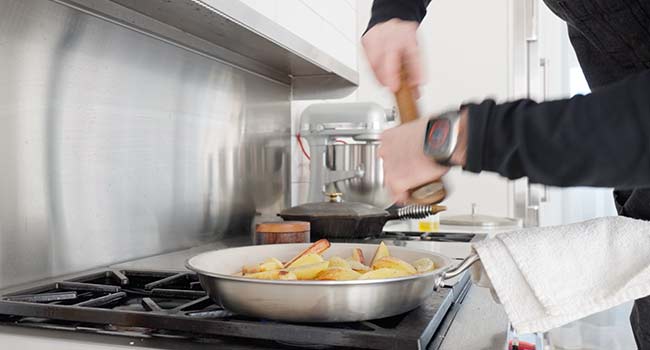 seasoning potatoes in a pan