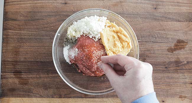 adding hamburger steak ingredients to a bowl