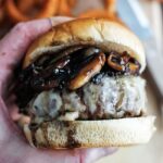 holding a mushroom swiss burger