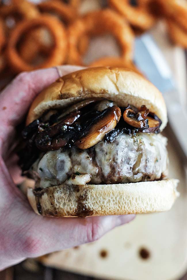 holding a mushroom swiss burger 