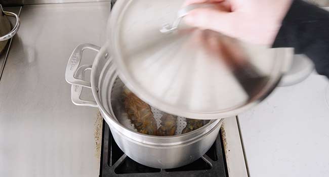 adding a lid to steaming lobster tails