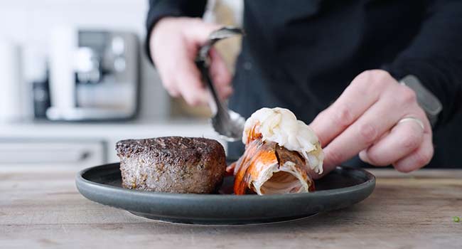 adding a lobster tail to plate with steak