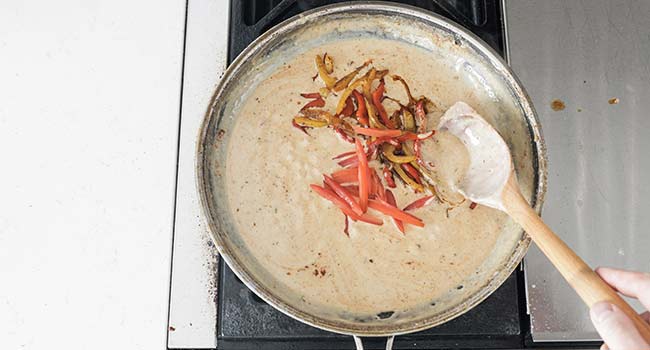 adding peppers and tomatoes to a cream sauce