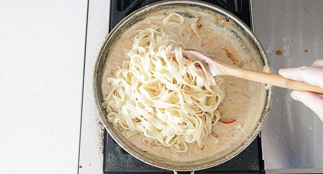 mixing pasta with a cream sauce