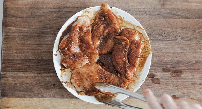 mixing chicken in a spice blend