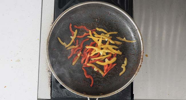 sautéing bell peppers in a pan