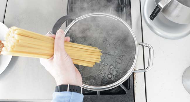 adding fettuccine to hot boiling water