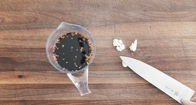 smashing garlic cloves for a soy sauce marinade